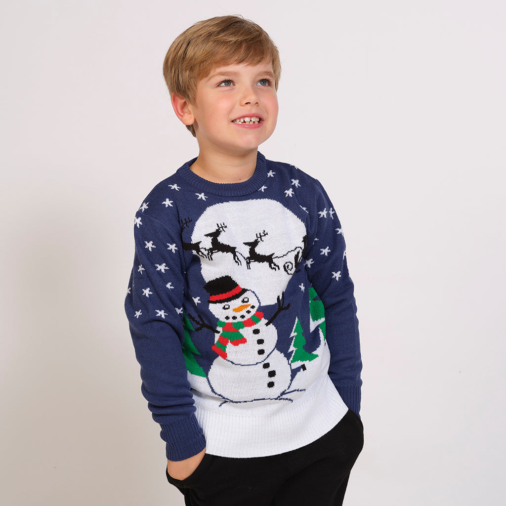 Et barn i blå julegenser med snømann på.